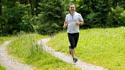 Ein Mann mittleren Alters joggt auf einem Feldweg.