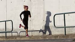 Guter Laufstil Eine Läuferin mit einem guten Laufstil läuft eine leichte Steigung bergauf.