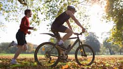 Ein Läufer und ein Radfahrer trainieren gemeinsam im Park.