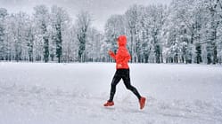 Snow Running: Eine Läuferin läuft durch einen tief verschneiten Park