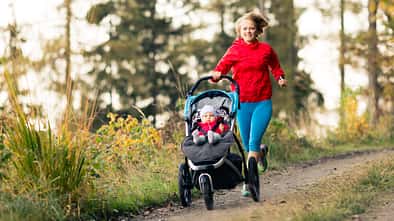 Joggen nach Kaiserschnitt: Laufende Mutter mit ihrem Kind in einem Babyjogger