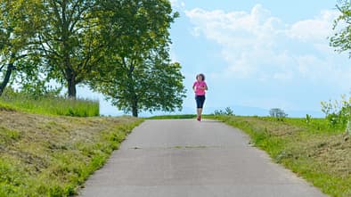 Welche Geschwindigkeit beim Joggen? Eine Frau läuft entspannt auf einer Straße.