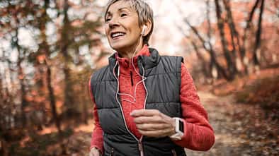 Trainingsplan: Erster Halbmarathon mit Ü60. Sportliche ältere Frau joggt im Wald.
