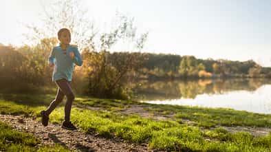 Ein Kind läuft auf einer schönen Strecke entlang eines Sees.