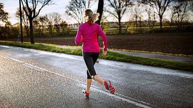 Frau beim Lauftraining auf regennasser Straße