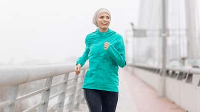 Eine Läuferin mit Kopftuch trainiert an einem nieseligen Morgen.