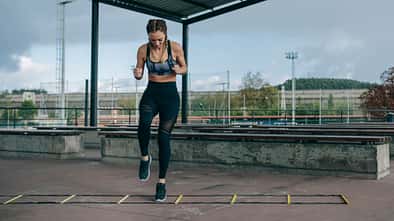 Hybrid-Training: Eine Sportlerin trainiert an einer Koordinationsleiter.