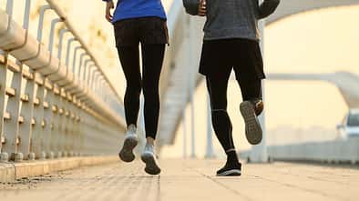 Joggen mit O-Beinen: Nahaufnahme einer Läuferin und eines Läufers von hinten, sie hat leichte X-Beine, er O-Beine.