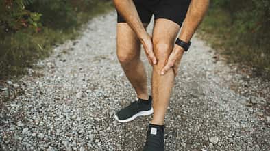 Ein Läufer hält seine schmerzende Wade.