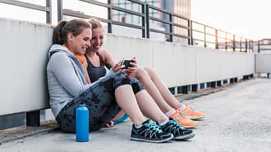 Zwei Läuferinnen schauen auf ein Smartphone