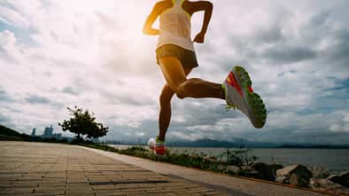 Schnelligkeit: Eine Läuferin rennt mit hohem Tempo auf einer Promenade am Meer.