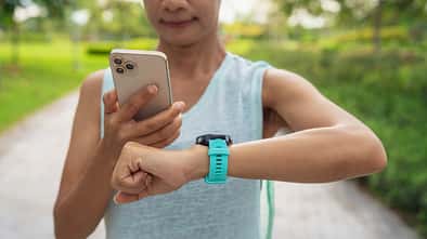 MET: das metabolische Äquivalent beim Laufen. Eine Läuferin checkt Lauf-Uhr und Lauf-App.