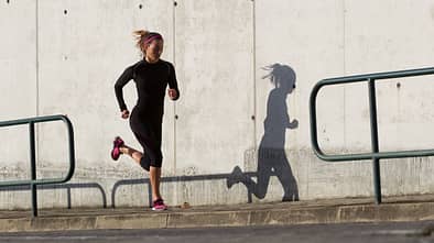 Eine Läuferin mit einem guten Laufstil läuft eine leichte Steigung bergauf.