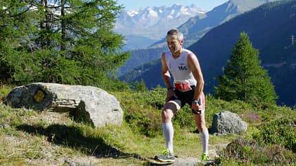 Teilnehmer steigt vor Gebirgspanorama den Berg hinauf Teilnehmer steigt vor Gebirgspanorama den Berg hinauf