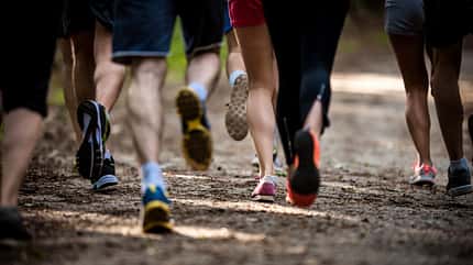 Large group of unrecognizable athletes running a marathon in nature.