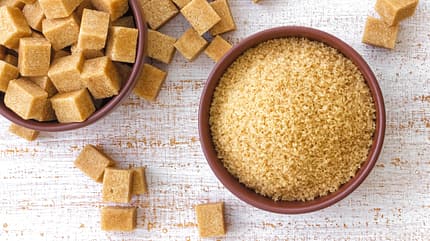 A bowl of brown sugar with sugar cubes on the side