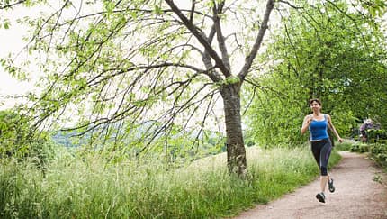 Laeuferin auf einem Weg entlang einer Wiese