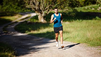 Sportlicher Läufer trainiert auf einem Schotterweg