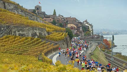Dutzende Teilnehmende am Lausanne-Marathon laufen entlang der Serpentinen zwischen Weinbergen und dem Genfer See.