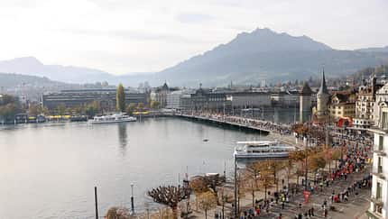 Panoramaasblick in den Luzerner Süden. Die Teilnehmenden laufen über die Seebrücke, die über die Reuss führt. Die Reuss mündet an dieser Stelle in den Vierwaldstätter See.
