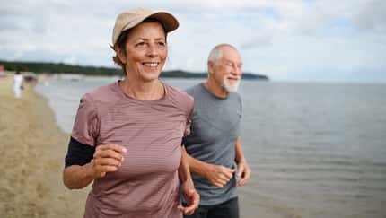 Ein sportliches, älteres Paar joggt am Strand.