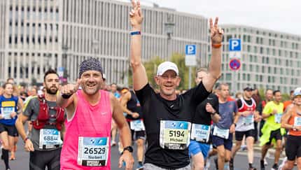 Zwei Läufer um die 50 jubeln beim Berlin-Marathon.