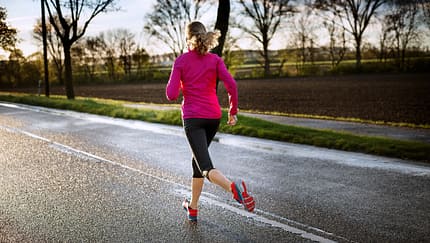 Frau beim Lauftraining auf regennasser Straße