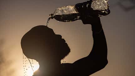 Hitze: Ein Mann schüttet sich Wasser aus einer Flasche über den Kopf.