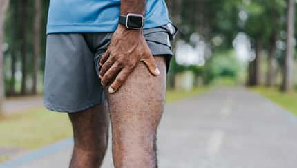Joggen mit Muskelkater: Ein Läufer fasst sich an den schmerzenden Oberschenkel.