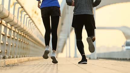 Joggen mit O-Beinen: Nahaufnahme einer Läuferin und eines Läufers von hinten, sie hat leichte X-Beine, er O-Beine.
