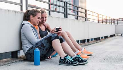 Zwei Läuferinnen schauen auf ein Smartphone