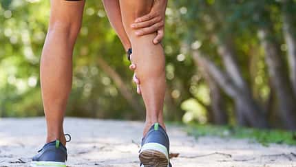 Close up of man holding calf in pain, sports injury trail run, cramp
