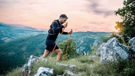 Speed Hiking: Ein Sportler besteigt mit Wanderstöcken einen Berg.