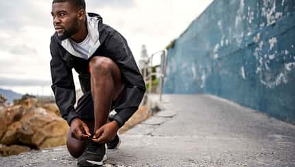 Ein Läufer schnürt seine Schuhe und blickt in die Ferne Ein Läufer schnürt seine Schuhe und blickt in die Ferne