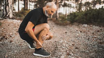 Ein Läufer hält sich den schmerzenden Knöchel.