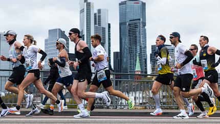 Eine Gruppe Läufer vor der Frankfurter Skyline. 