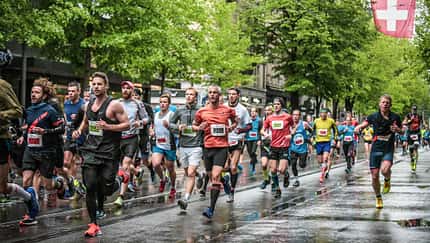 Läufer auf regennasser Straße, Schweiz-Flagge im Hintergrund. Läufer auf regennasser Straße, Schweiz-Flagge im Hintergrund.