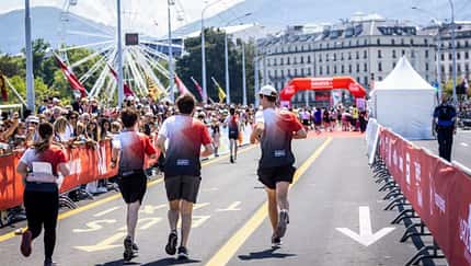 Vier Läufer in passenden Team-Trikots laufen Richtung Ziel, Riesenrad im Hintergrund. Vier Läufer in passenden Team-Trikots laufen Richtung Ziel, Riesenrad im Hintergrund.