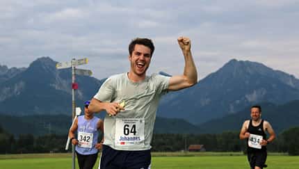 Ein Läufer mit erhobenem Arm, dahinter Alpen-Panorama. Ein Läufer mit erhobenem Arm, dahinter Alpen-Panorama.