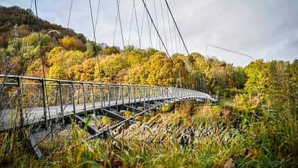 Hängebrücke mit buntem Herbstwald im Hintergrund. Hängebrücke mit buntem Herbstwald im Hintergrund.