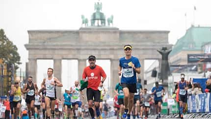 Vor dem Brandenburger Tor laufen Läufer angestrengt beim Marathon