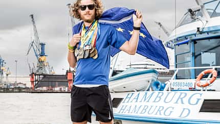 Tim ­Teege im Hamburger ­Hafen mit einer kleinen Auswahl der Finisher­medaillen der letzten Jahre.