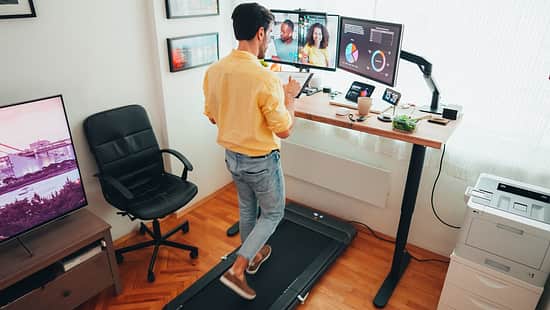 Ein Mann geht am Schreibtisch auf einem Walkingpad.