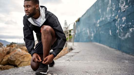 Ein Läufer schnürt seine Schuhe und blickt in die Ferne