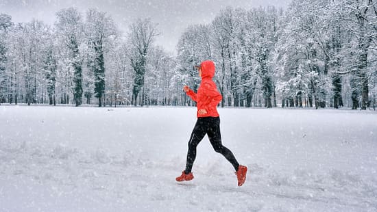 Snow Running: Eine Läuferin läuft durch einen tief verschneiten Park