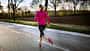 Frau beim Lauftraining auf regennasser Straße