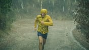 Mann in Regenjacke läuft durch strömenden Regen.