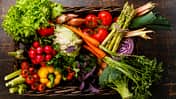 Fresh vegetables in basket on wooden background