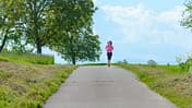 Welche Geschwindigkeit beim Joggen? Eine Frau läuft entspannt auf einer Straße.