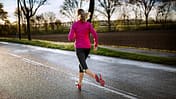 Frau beim Lauftraining auf regennasser Straße